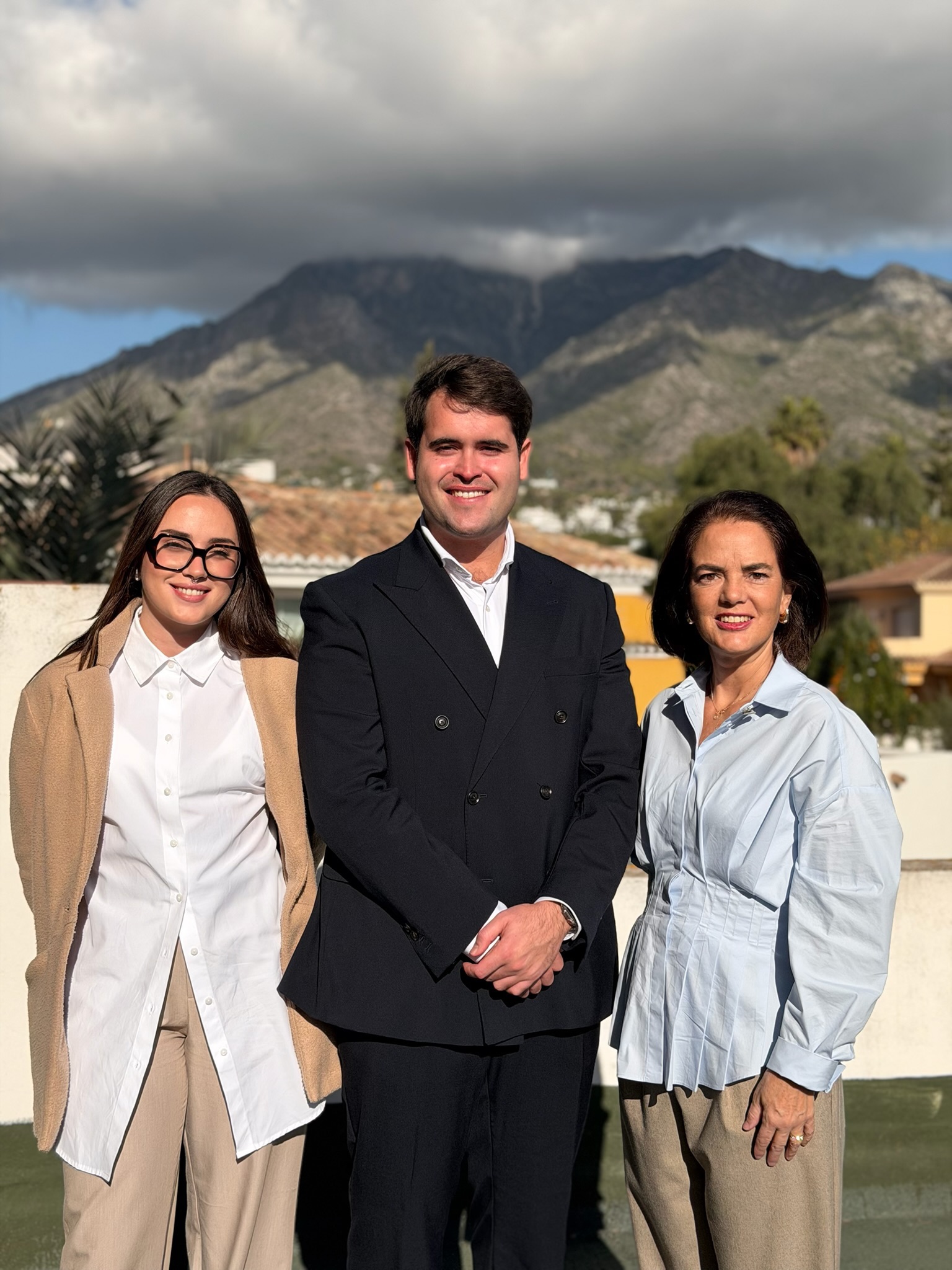 Tre medarbetare från Global Accounting står tillsammans och ler, klädda i affärsmässiga kläder i en professionell miljö.